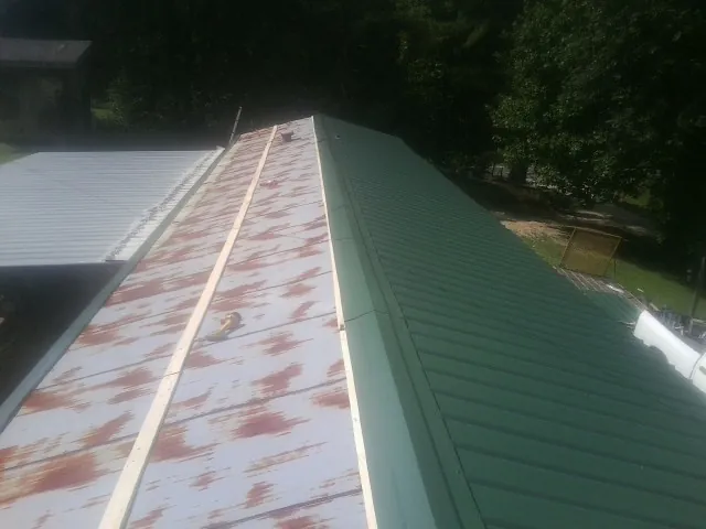 Old rusted panels beside newly installed green metal roofing — Wind Damage Roof Repair by Roofing Brothers in Walpole