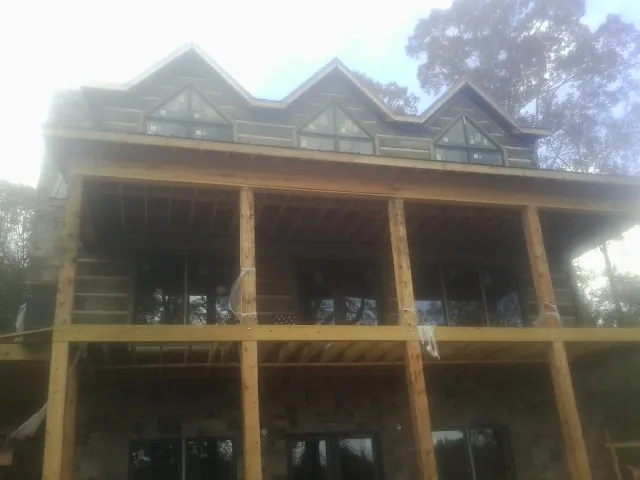 Dormers and porch framing on a large log home under construction — Roof Coating work by our crew in Walpole