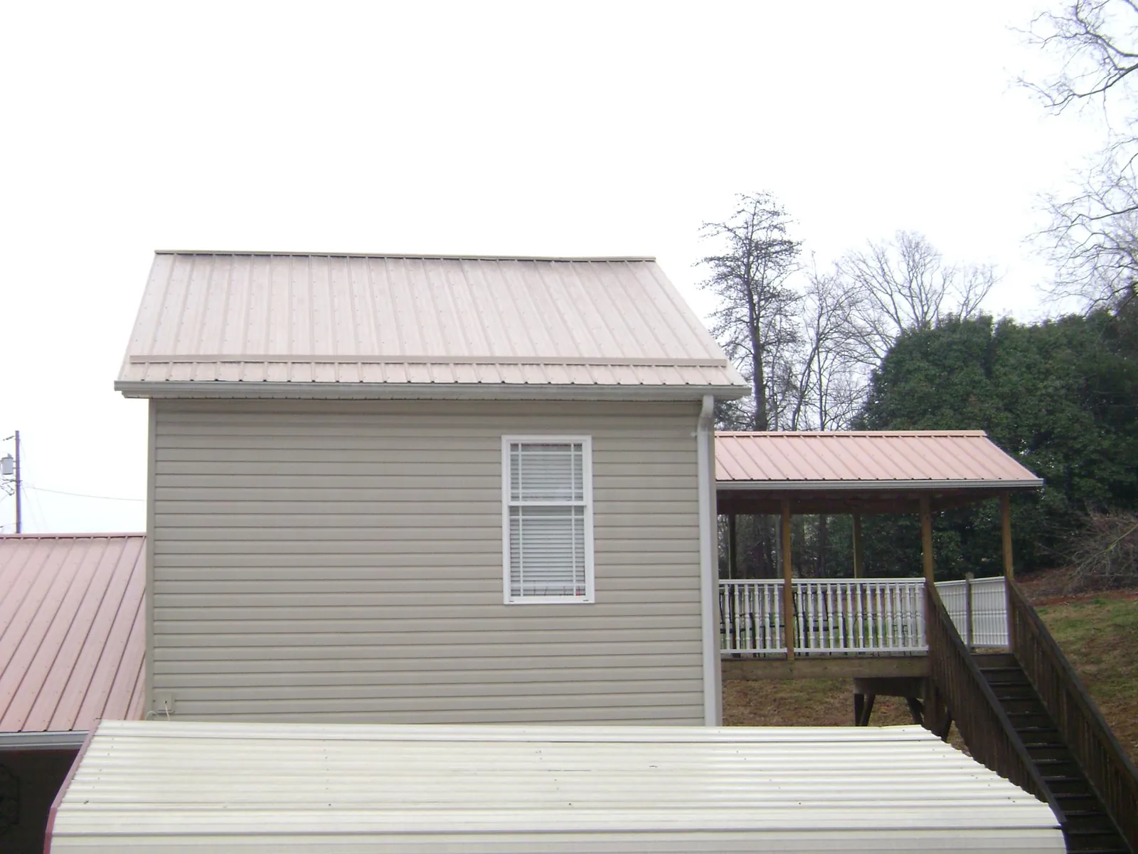 Tan metal roofs on a two story addition and attached porch, from a Roof Replacement job in Walpole