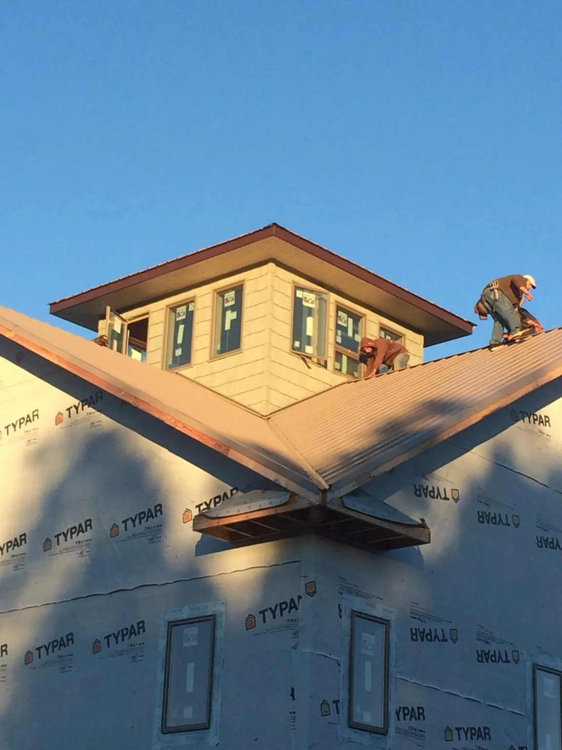 Roofers working around a rooftop cupola on a new metal roof at sunset — Roof Waterproofing in Walpole by Roofing Brothers